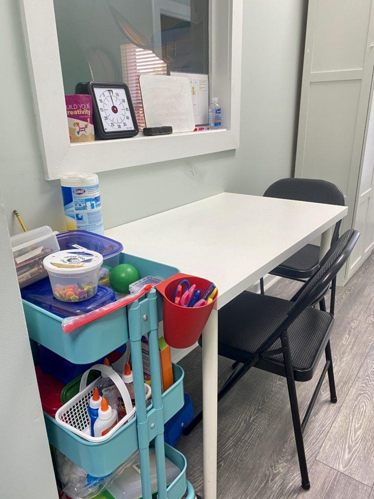 Therapy workspace with table, chairs, and supply cart